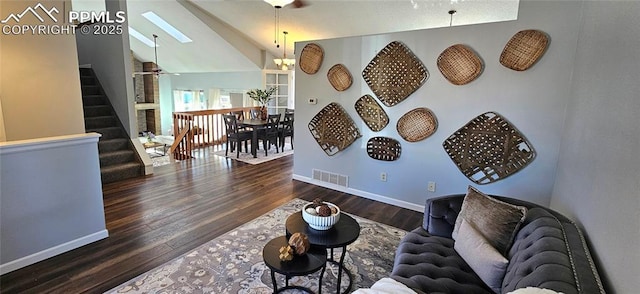 living room featuring wood finished floors, visible vents, baseboards, vaulted ceiling with skylight, and stairs