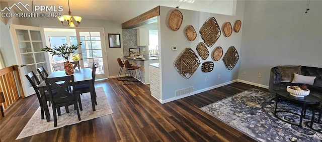 dining room with a notable chandelier, visible vents, baseboards, and wood finished floors