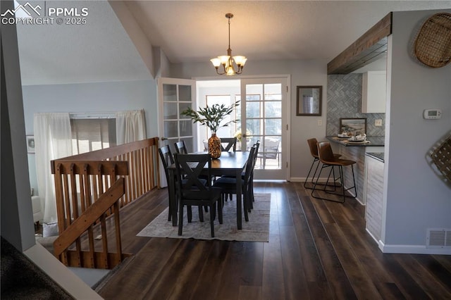 dining area featuring visible vents, baseboards, dark wood-type flooring, and a chandelier