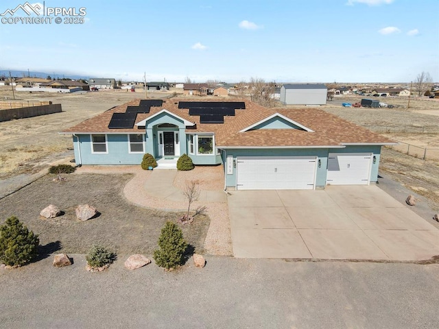 view of front of house featuring fence, roof mounted solar panels, stucco siding, a garage, and driveway