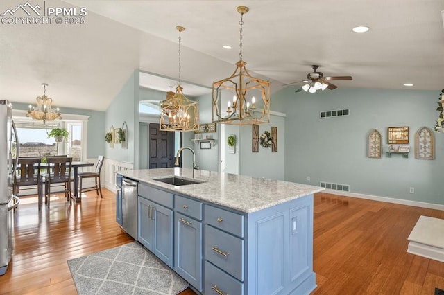 kitchen featuring visible vents, a sink, vaulted ceiling, light wood-style floors, and appliances with stainless steel finishes