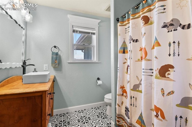 bathroom featuring vanity, visible vents, baseboards, tile patterned flooring, and toilet