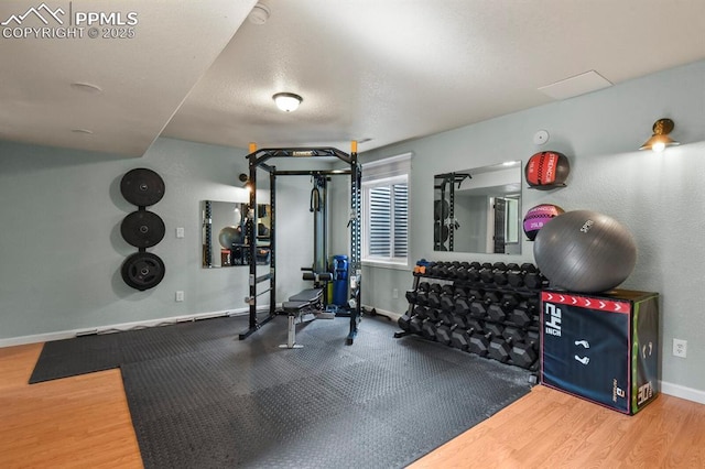 exercise room featuring baseboards and wood finished floors