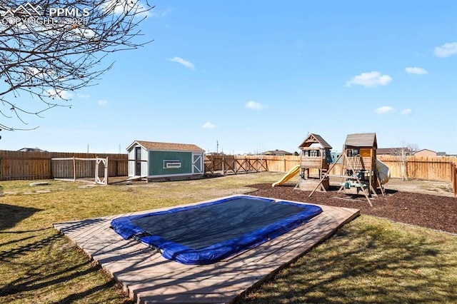 view of yard with a trampoline, a fenced backyard, a playground, a shed, and an outdoor structure