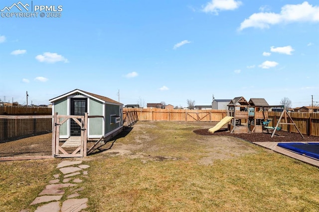 view of yard with a fenced backyard, an outdoor structure, exterior structure, and a playground