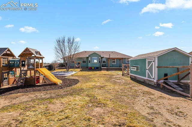 view of yard with a storage unit, fence, an outdoor structure, and a playground