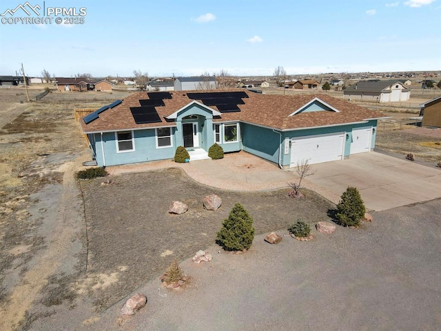 ranch-style house with roof mounted solar panels, a garage, driveway, and stucco siding