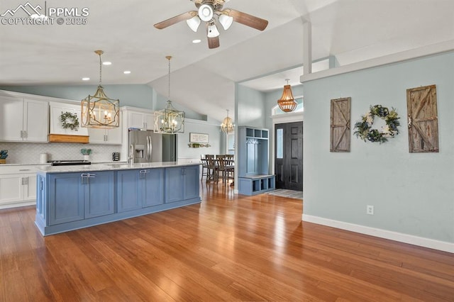 kitchen with lofted ceiling, white cabinets, stainless steel refrigerator with ice dispenser, and backsplash