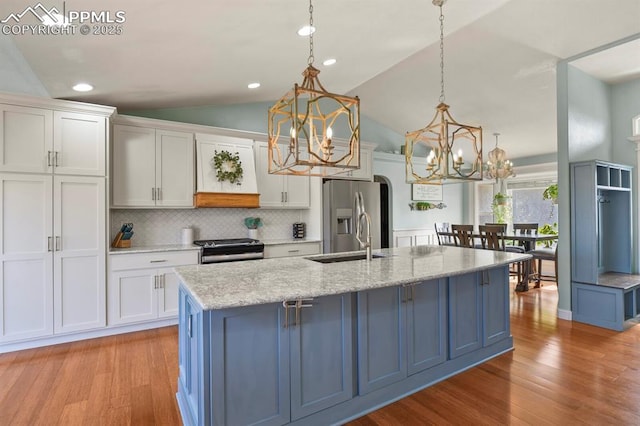 kitchen with a sink, appliances with stainless steel finishes, light wood-style flooring, and white cabinets