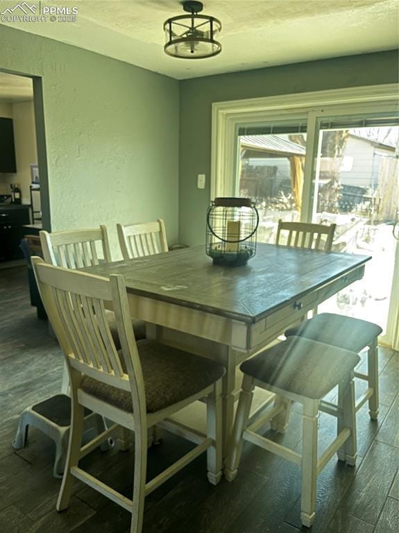 dining space with a textured ceiling, wood finished floors, and a textured wall