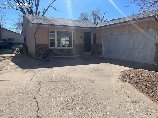 view of front of home featuring stone siding, an attached garage, board and batten siding, and driveway