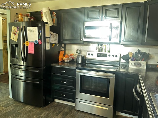 kitchen featuring dark wood-style floors, backsplash, stainless steel appliances, and dark cabinets