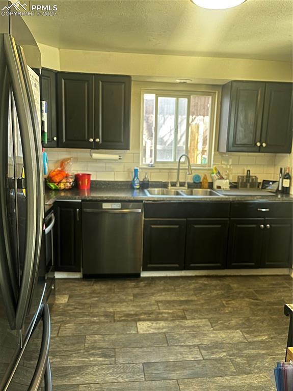 kitchen featuring decorative backsplash, dark countertops, appliances with stainless steel finishes, and a sink