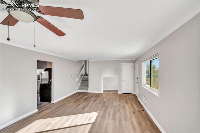 unfurnished living room with ornamental molding, wood finished floors, stairway, baseboards, and ceiling fan