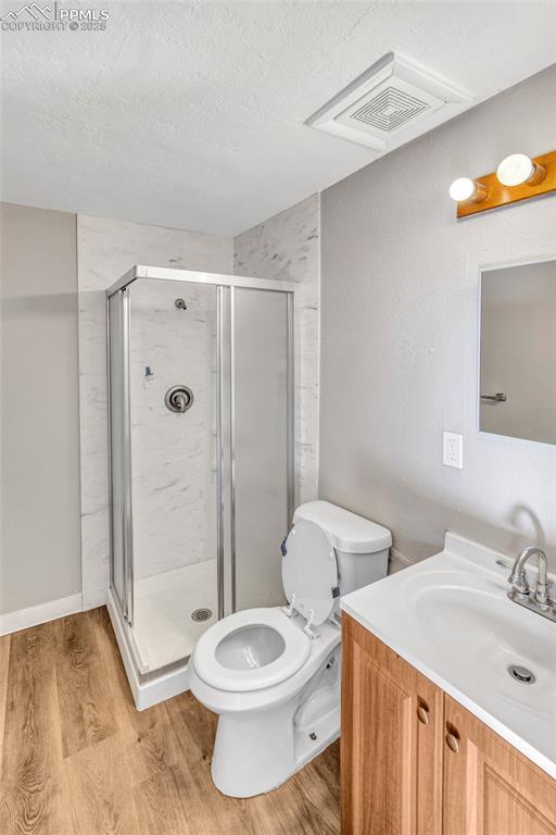 bathroom featuring a stall shower, toilet, and wood finished floors