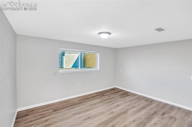 spare room featuring visible vents, baseboards, and wood finished floors