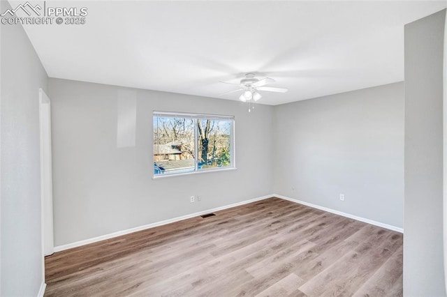 empty room featuring baseboards, wood finished floors, visible vents, and ceiling fan