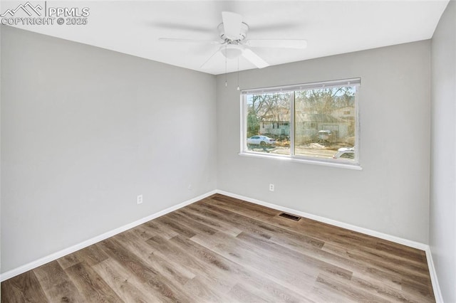 unfurnished room featuring visible vents, baseboards, wood finished floors, and a ceiling fan