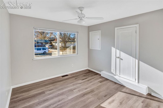 empty room with visible vents, a ceiling fan, baseboards, and wood finished floors