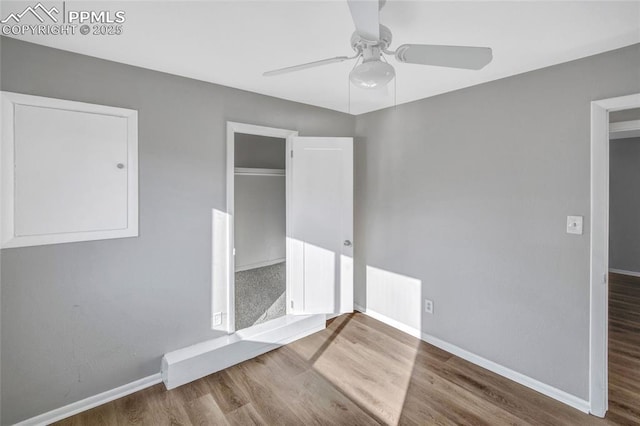 unfurnished bedroom featuring wood finished floors, baseboards, a closet, and ceiling fan