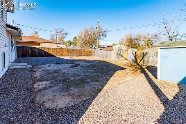 view of yard with a storage unit, an outbuilding, and a fenced backyard