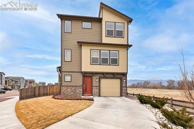 view of front facade with stone siding, concrete driveway, an attached garage, and fence