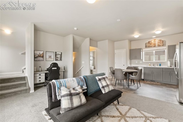 living area featuring stairway and light colored carpet