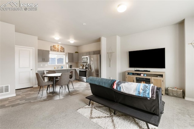 living room with visible vents, light carpet, and baseboards