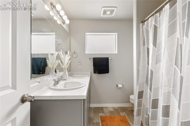 bathroom with a sink, visible vents, toilet, and double vanity