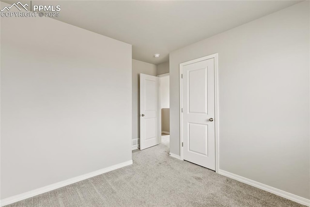 spare room featuring baseboards and light carpet