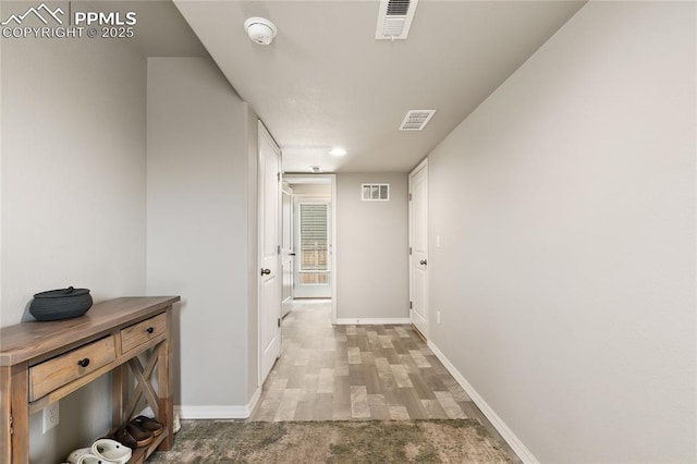 hall featuring baseboards and visible vents