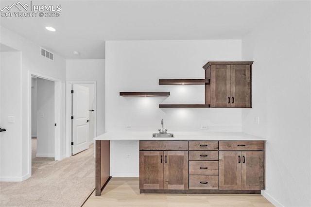 kitchen with visible vents, open shelves, light countertops, and a sink