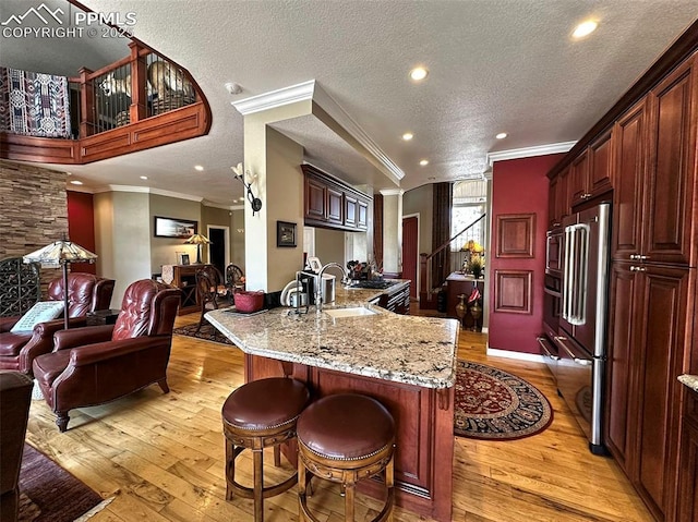 kitchen featuring light wood finished floors, a peninsula, a kitchen bar, and a sink