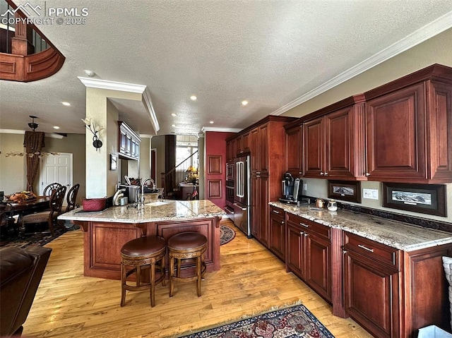 kitchen with light wood finished floors, a kitchen breakfast bar, and ornamental molding