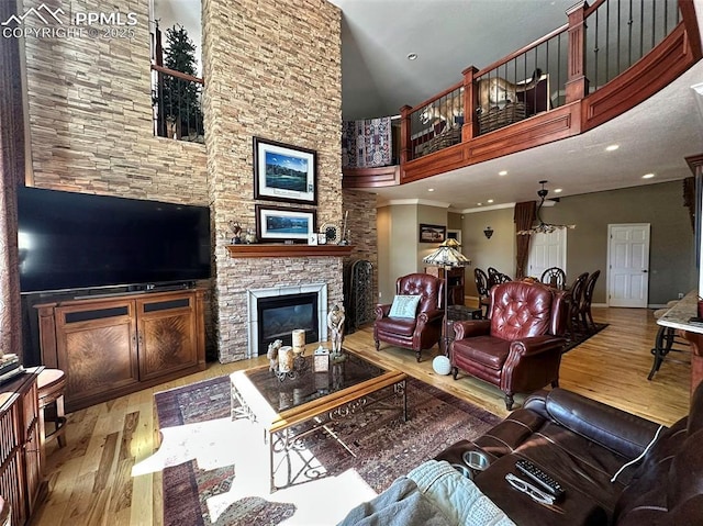 living room featuring wood finished floors, a high ceiling, a stone fireplace, crown molding, and baseboards