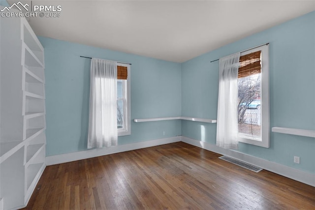 spare room with hardwood / wood-style floors, baseboards, and visible vents