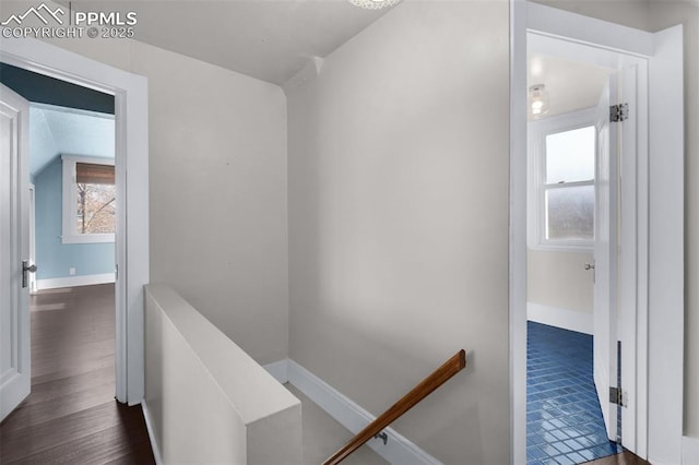 corridor featuring baseboards, an upstairs landing, dark wood finished floors, and vaulted ceiling