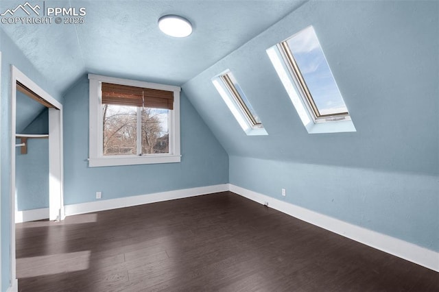 bonus room featuring dark wood finished floors, vaulted ceiling, baseboards, and a textured ceiling