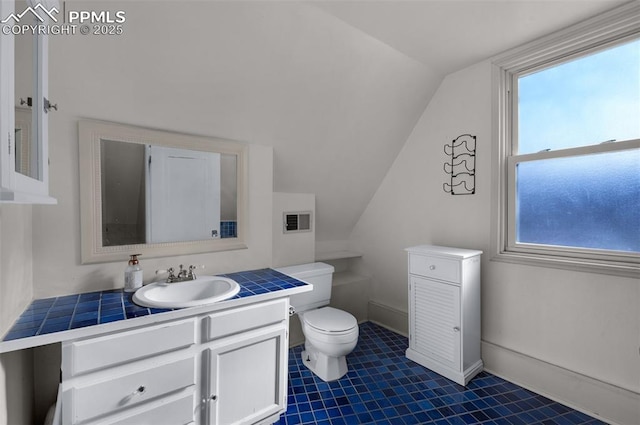 bathroom featuring vanity, lofted ceiling, toilet, and baseboards