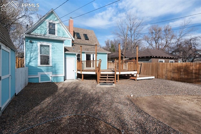 rear view of property featuring a deck, a fenced backyard, a shingled roof, and a chimney