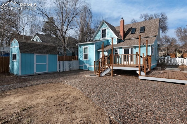 rear view of property with a wooden deck, fence, an outdoor structure, and a shed