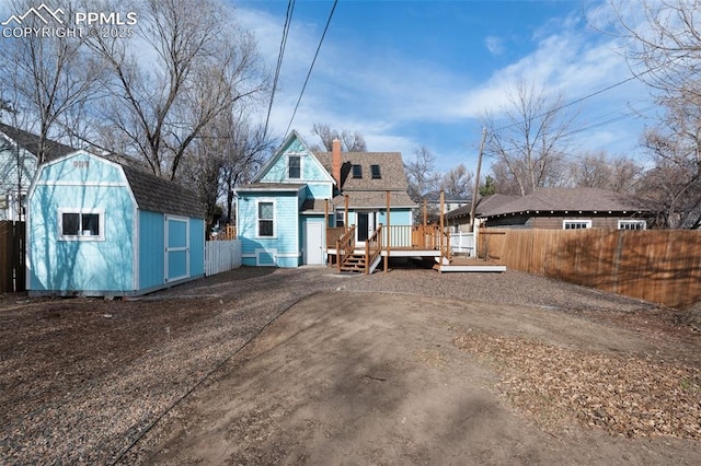 back of house with a gambrel roof, a fenced backyard, and a deck