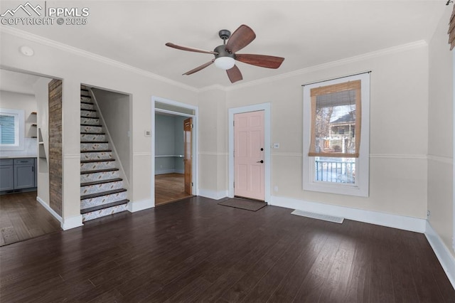 unfurnished living room featuring crown molding, ceiling fan, dark wood-type flooring, baseboards, and stairway