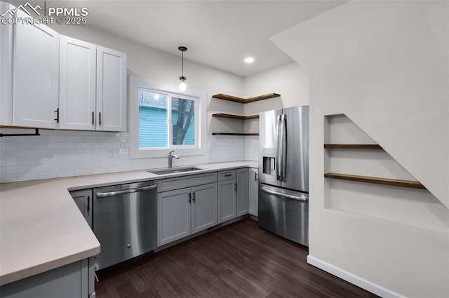 kitchen featuring a sink, open shelves, appliances with stainless steel finishes, light countertops, and dark wood-style flooring