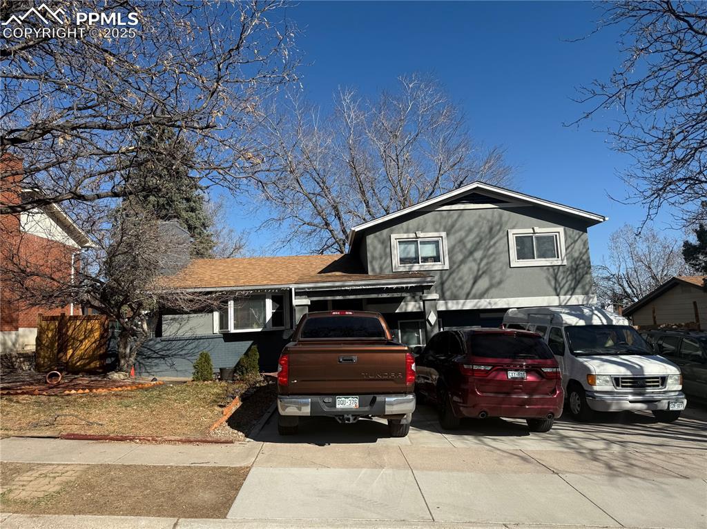 split level home featuring a garage, a chimney, and driveway