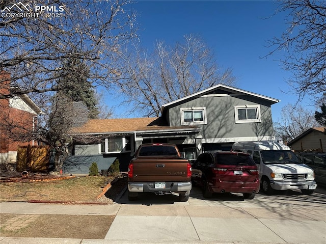 split level home featuring a garage, a chimney, and driveway