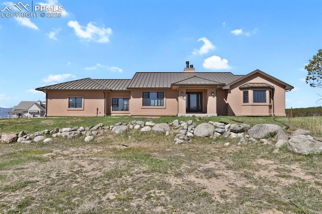 14060 Black Forest Rd, Colorado Springs, CO 80908 - rear view of property featuring a chimney, a standing seam roof, stucco siding, and metal roof
