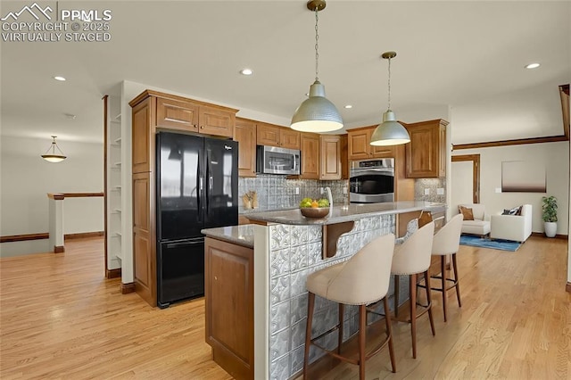 14060 Black Forest Rd, Colorado Springs, CO 80908 - kitchen featuring tasteful backsplash, brown cabinetry, a breakfast bar area, light wood finished floors, and appliances with stainless steel finishes