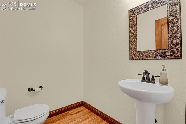 14060 Black Forest Rd, Colorado Springs, CO 80908 - half bathroom featuring baseboards, wood finished floors, a sink, and toilet