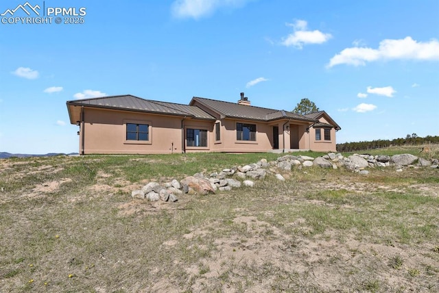 14060 Black Forest Rd, Colorado Springs, CO 80908 - back of property featuring stucco siding, a chimney, a standing seam roof, and metal roof